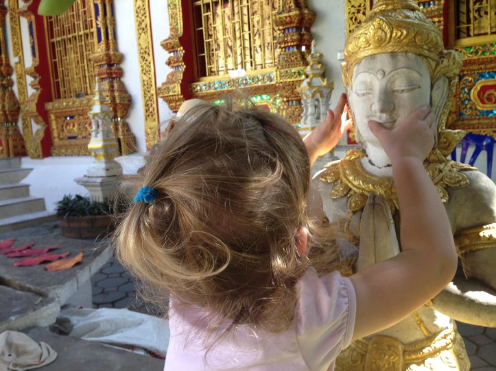 Bambina e statua di Buddha nel cortile di un monastero, Chiang Mai, Thailandia