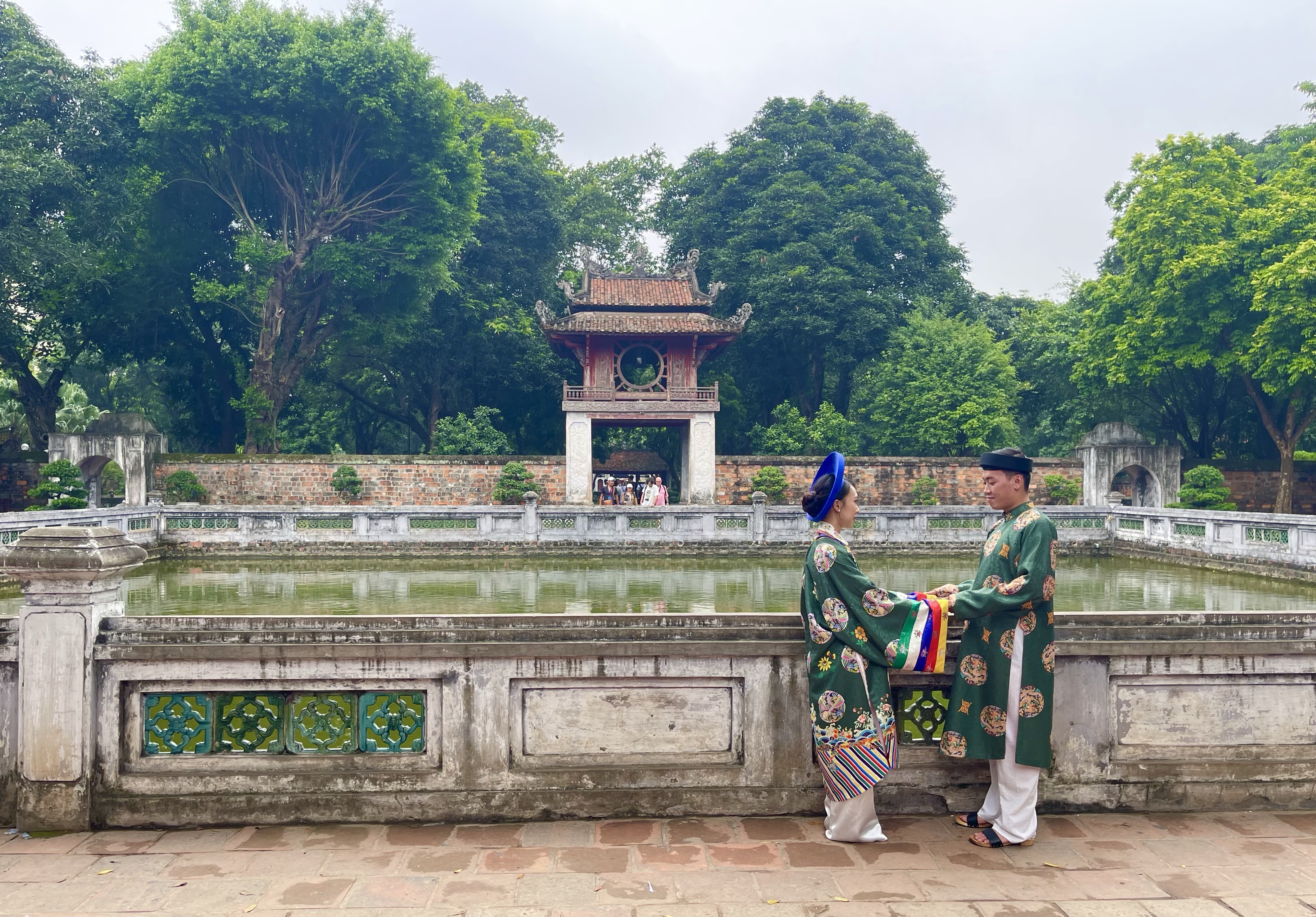 Coppia di sposi in abito verde tradizionale, in posa al tempio della letteratura di Hanoi 
